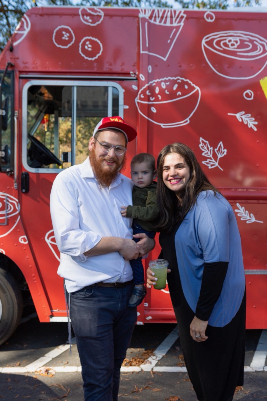Two adults and a child in front of the Yalla food truck