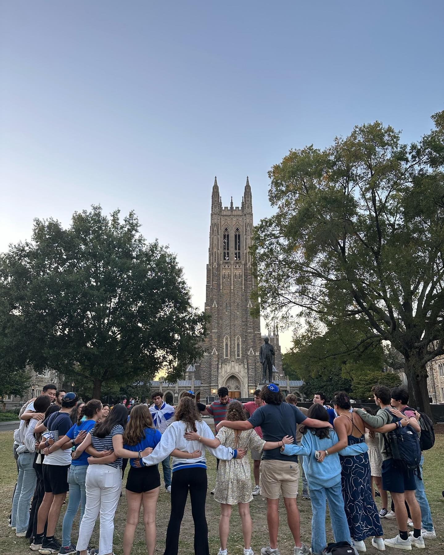 Chabad at Duke students standing in a circle in front of Duke Chapel at golden hour