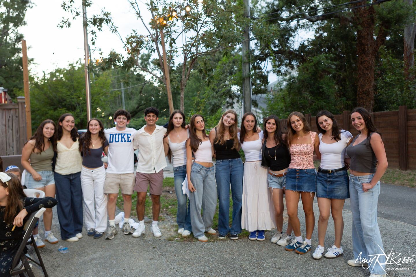 A big group of friends smiling together at dusk in the backyard