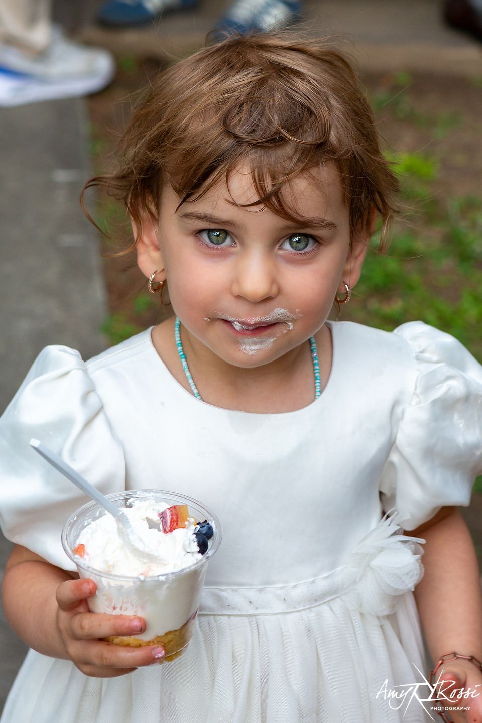 A little girl eating ice cream on the steps during graduation weekend