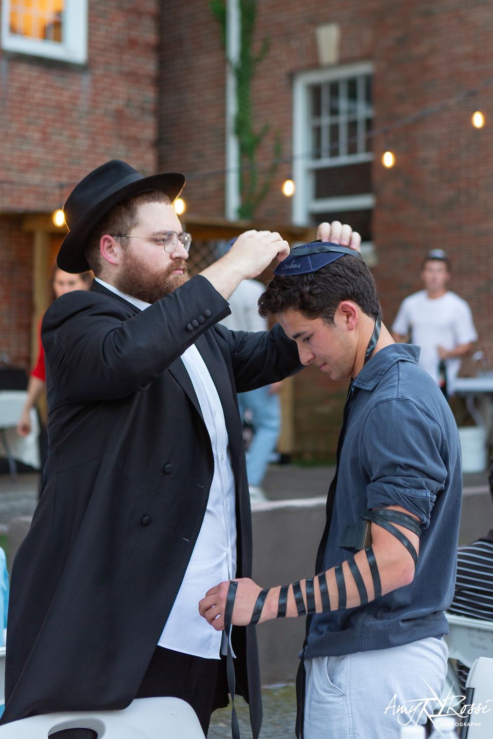 Rabbi Nossen helping a student wrap tefillin at sunset